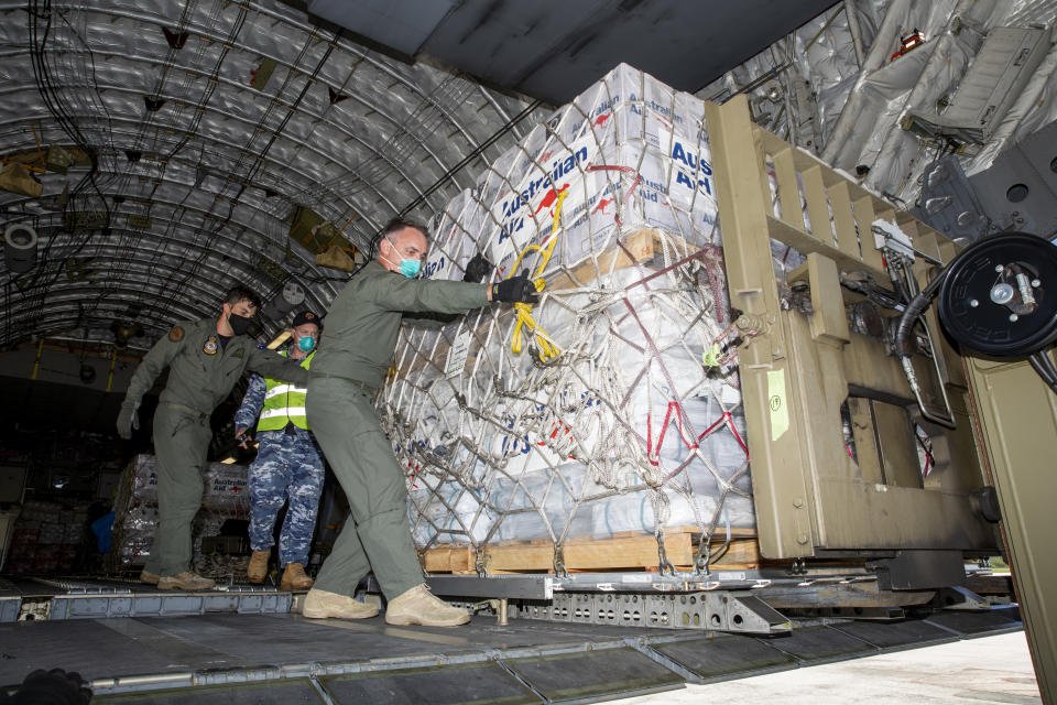 In this photo provided by the Australian Defence Force, personnel unload emergency aid supplies at Tonga's Fuaʻamotu International Airport, near Nukuʻalofa, Thursday, Jan. 20, 2022, after a volcano eruption. U.N. humanitarian officials report that about 84,000 people — more than 80% of Tonga's population — have been impacted by the volcano's eruption. (LACW Emma Schwenke/Australia Defence Force via AP)