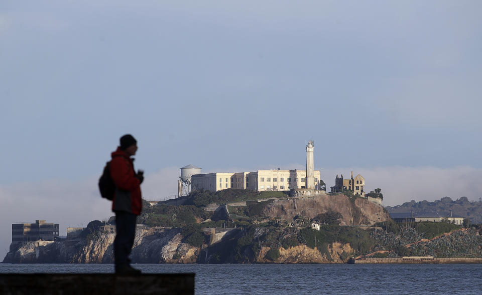 A man stands on a pier with Alcatraz Island in the background in San Francisco, Dec. 22, 2018. The company that provides ferry services to Alcatraz Island kept its daytime tours but canceled its behind-the-scenes and night tours on Saturday due to the government shutdown. (Photo: Jeff Chiu/AP)