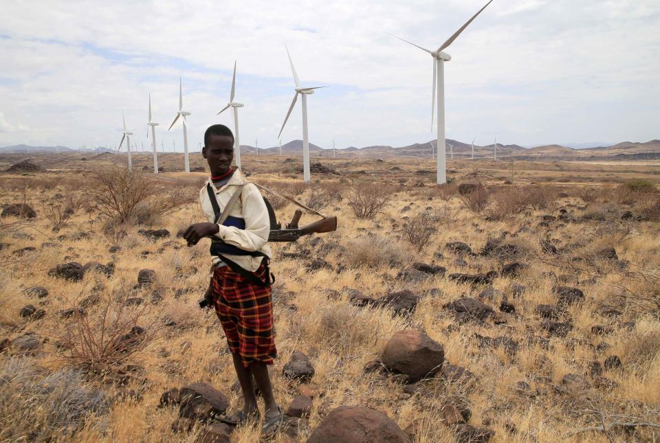 <p>Ein Hirtenjunge in Turkana County in Kenia trägt ein Gewehr, während er seine Herde an den Windturbinen vorbei am Lake Turkana Windstrom-Projekt im im nordkenianischen Marsabit vorantreibt. (Bild: REUTERS/Thomas Mukoya) </p>