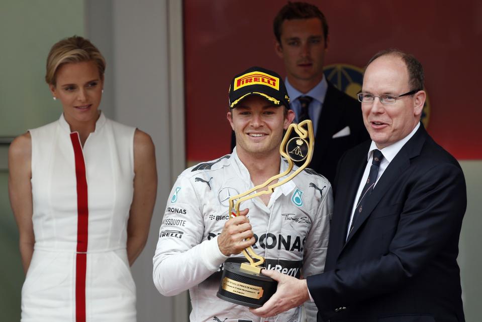 Mercedes Formula One driver Nico Rosberg (C) of Germany receives his trophy from Prince Albert II of Monaco (R) while Princess Charlene looks on after Rosberg won the Monaco F1 Grand Prix in Monaco May 25, 2014. Rosberg won the showcase Monaco Grand Prix for the second year in a row on Sunday to snatch back the Formula One world championship lead from Mercedes team mate Lewis Hamilton.REUTERS/Stefano Rellandini (MONACO - Tags: SPORT MOTORSPORT F1 ROYALS ENTERTAINMENT)