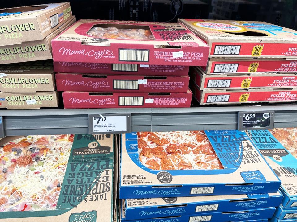 Several cardboard boxes with red, green, and blue designs containing frozen pizzas on shelves at Aldi