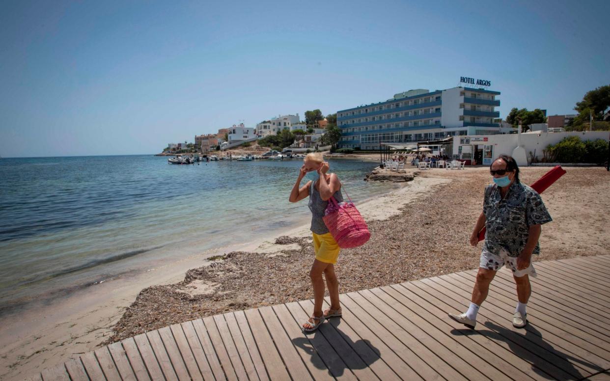 People wearing face masks arrive at Talamanca beach in Ibiza - JAIME REINA /AFP