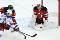 New York Rangers center Brett Howden (21) shoots as New Jersey Devils goaltender Mackenzie Blackwood (29) makes a save with Devils defenseman Will Butcher (8) looking on during the first period of an NHL hockey game, Tuesday, April 13, 2021, in Newark, N.J. (AP Photo/Kathy Willens)