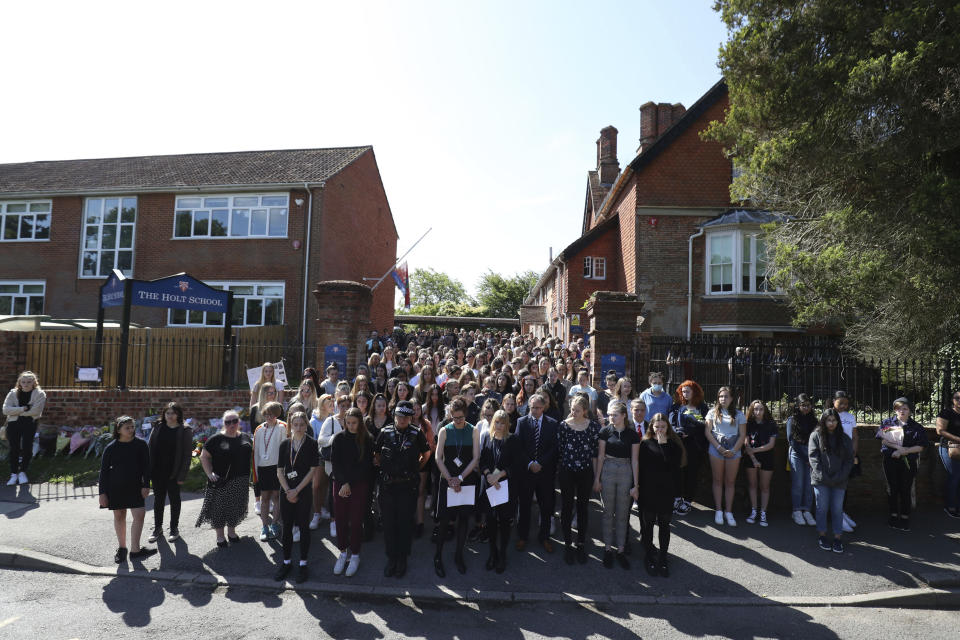 Colleagues and pupils of teacher James Furlong stand together to take part in a period of silence at the Holt School, in Wokingham, England, in memory of teacher James Furlong, a victim of a terror attack in nearby Reading, Monday June 22, 2020.  A lone terror suspect remains in custody accused of killing three people and wounding three others in a Reading park on Saturday night. (Steve Parsons/PA via AP)