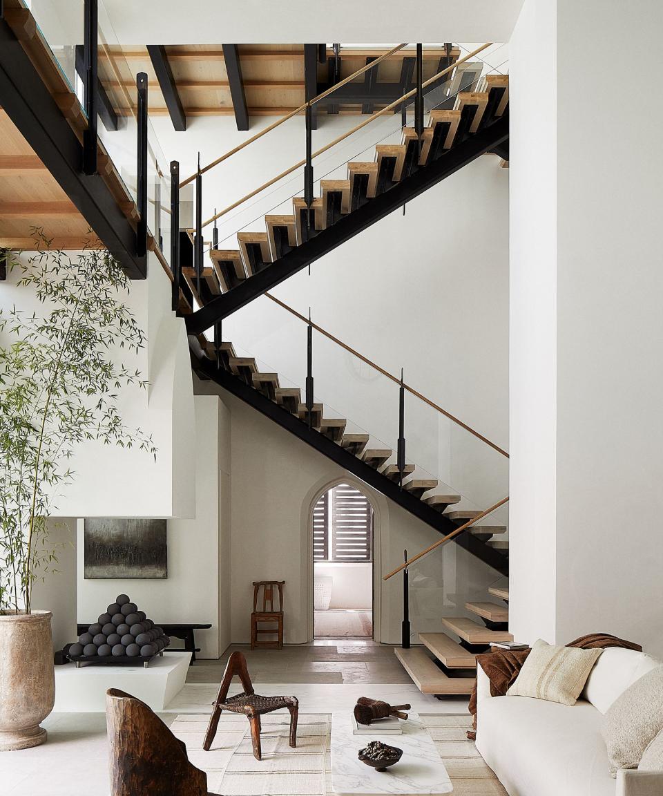 living room with staircase behind and white sofa and with white walls with central fireplace