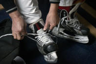 A member of the "1979" hockey club laces up his skates in the locker room before a match at a hockey rink in Beijing, Wednesday, Jan. 12, 2022. Spurred by enthusiasm after China was awarded the 2022 Winter Olympics, the members of a 1970s-era youth hockey team, now around 60 years old, have reunited decades later to once again take to the ice. (AP Photo/Mark Schiefelbein)