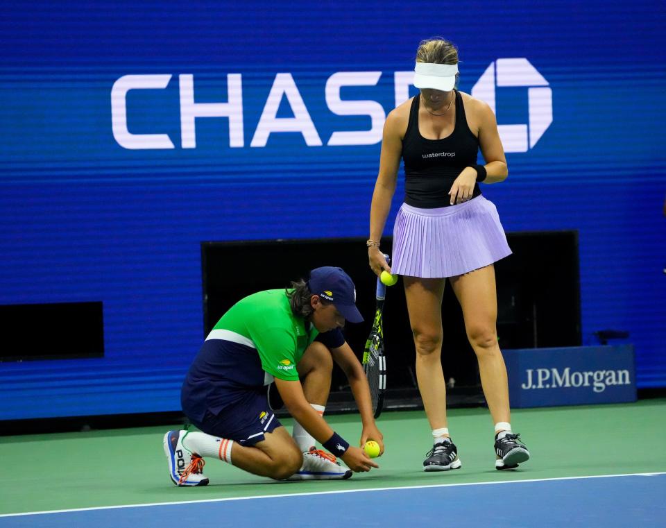 A ball person traps a bug during Danielle Collins' match vs Aryna Sabalenka at the 2022 US Open.