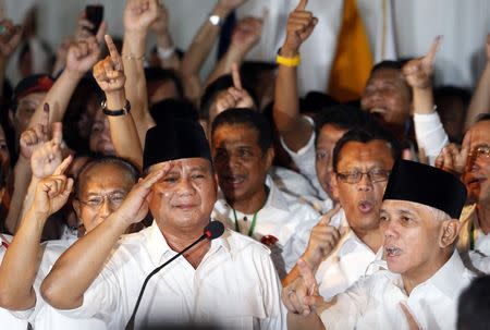 Indonesian presidential candidate Prabowo Subianto (R) gives a salute as his vice presidential running mate Hatta Rajasa (L) and supporters gesture after Prabowo declared victory in Jakarta July 9, 2014. REUTERS/Beawiharta