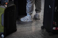 Un viajero, que lleva zapatos protectores, espera en la fila para embarcar en su vuelo en el aeropuerto de Narita. (AP Photo/Jae C. Hong)