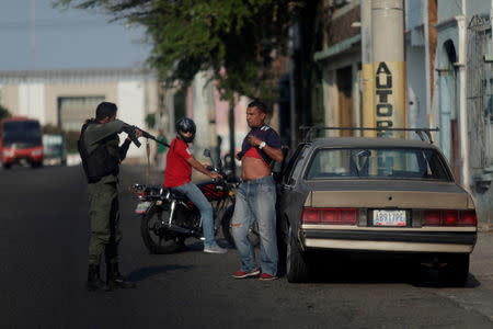 FILE PHOTO: A Venezuelan police officer orders a man to lift his shirt, during a blackout in Maracaibo, Venezuela, April 12, 2019. REUTERS/Ueslei Marcelino