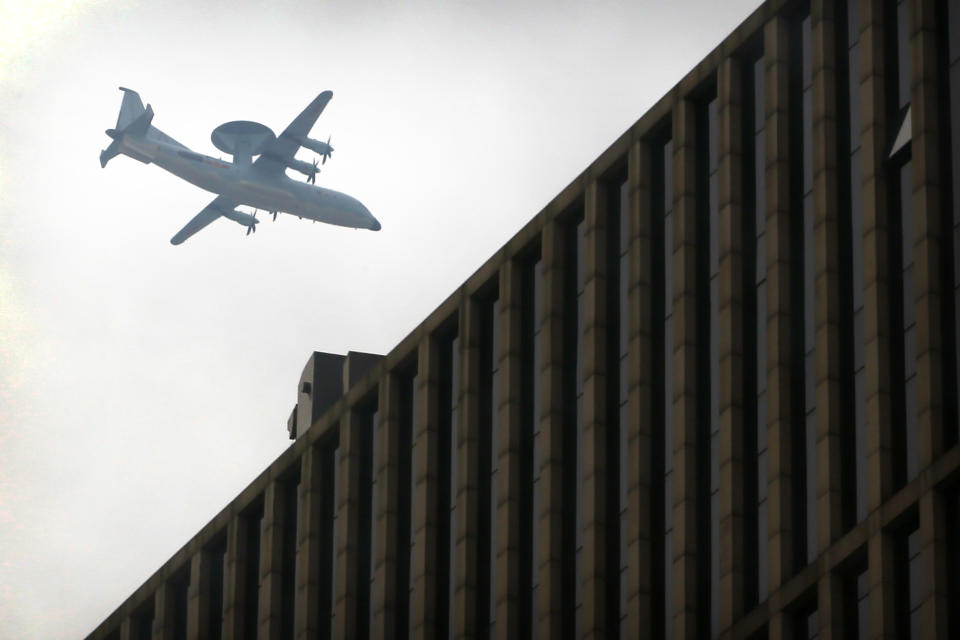 A Chinese military plane flies above the central business district in Beijing, Sunday, Sept. 15, 2019. Many of the streets in the central part of China's capital were shut down this weekend for a rehearsal for what is expected to be a large military parade on Oct. 1 to commemorate the 70th anniversary of Communist China. (AP Photo/Mark Schiefelbein)