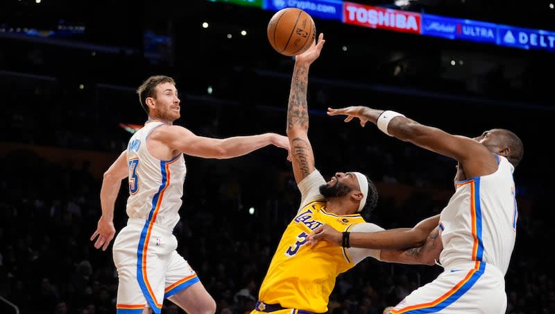 Los Angeles Lakers forward Anthony Davis (3) reaches for a rebound between Oklahoma City Thunder forward Gordon Hayward, left, and center Bismack Biyombo during a game Monday, March 4, 2024, in Los Angeles.