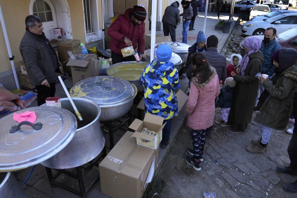 People wait to receive a hot meal, in Iskenderun city, southern Turkey, Tuesday, Feb. 14, 2023. Thousands left homeless by a massive earthquake that struck Turkey and Syria a week ago packed into crowded tents or lined up in the streets for hot meals as the desperate search for survivors entered what was likely its last hours. (AP Photo/Hussein Malla)