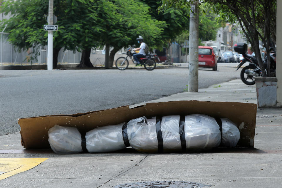 An abandoned corpse wrapped in plastic and covered with cardboard lies on the sidewalk in Guayaquil, Ecuador.. Source: Getty Images