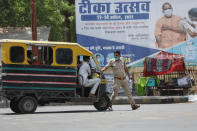 A police man stops an auto rickshaw at a check point during a weekend lockdown to curb the spread of coronavirus in Prayagraj, India, Sunday, April 18, 2021. (AP Photo/Rajesh Kumar Singh)