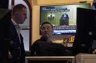 Traders work.on the floor of the New York Stock Exchange, Friday, Aug. 25, 2023, as Federal Reserve Chair Jerome Powell's speech shows on a television screen. Stocks are holding on to gains after Powell said more rate hikes could be on the way to continue the Fed's fight against inflation. (AP Photo/Richard Drew)