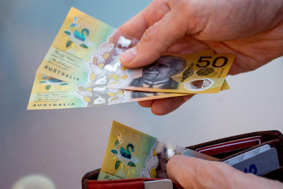 Hands holding wallet with australian dollars and make a payment - coronavirus finance struggle concept