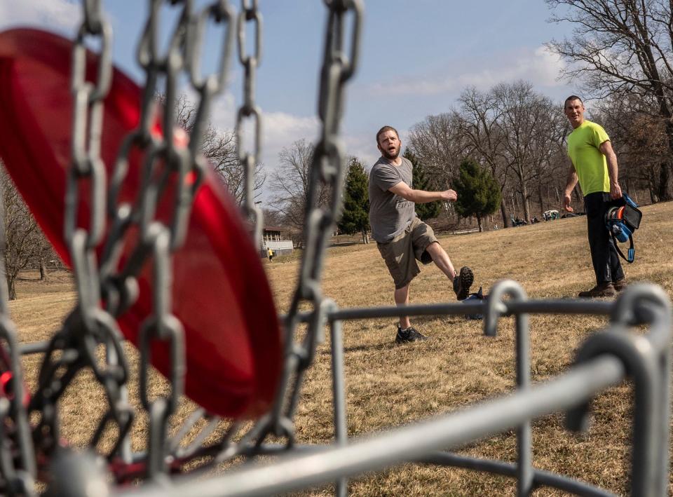 Jared Stephen, left, of Burton reacts after getting his disc in as his cousin John Kelley looks on while playing a game of disc golf at the Mott Park Disc Golf Course in Flint on Monday, March 4, 2024.