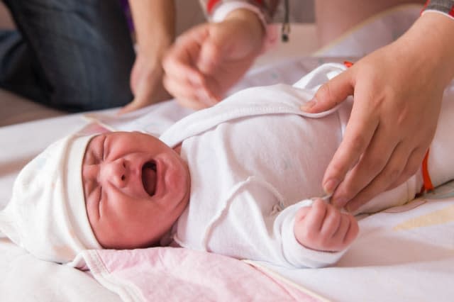 newborn baby crying on the bed  ...