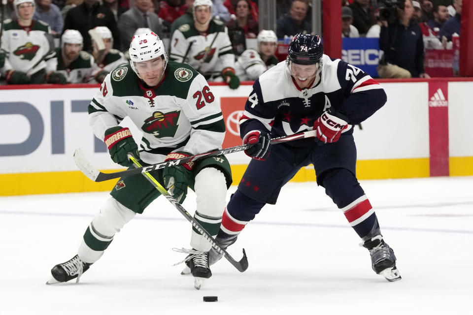 Minnesota Wild center Connor Dewar (26) and Washington Capitals center Connor McMichael (24) vie for control of the puck during the second period of an NHL hockey game Friday, Oct. 27, 2023, in Washington. (AP Photo/Mark Schiefelbein)