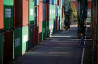 Workers walk between shipping containers at a port in Tokyo, Japan, March 22, 2017. REUTERS/Issei Kato