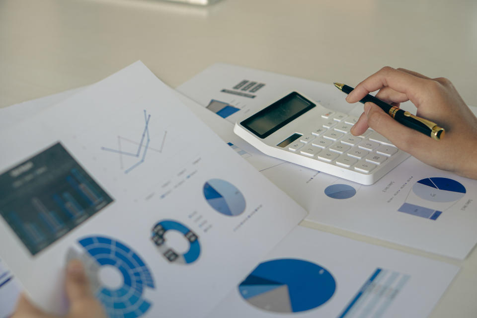 Close-up business concept of accountant holding graph document working on calculator to calculate financial data report Accounting documents and laptop computer at the office, close-up