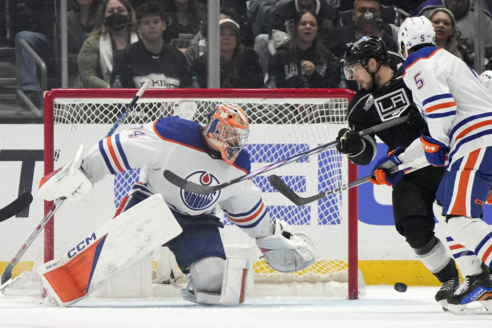 Edmonton Oilers goaltender Stuart Skinner, left, dives for the puck as Los Angeles Kings right wing Viktor Arvidsson, center, and defenseman Cody Ceci watch during the third period in Game 4 of an NHL hockey Stanley Cup first-round playoff series Sunday, April 28, 2024, in Los Angeles. (AP Photo/Mark J. Terrill)