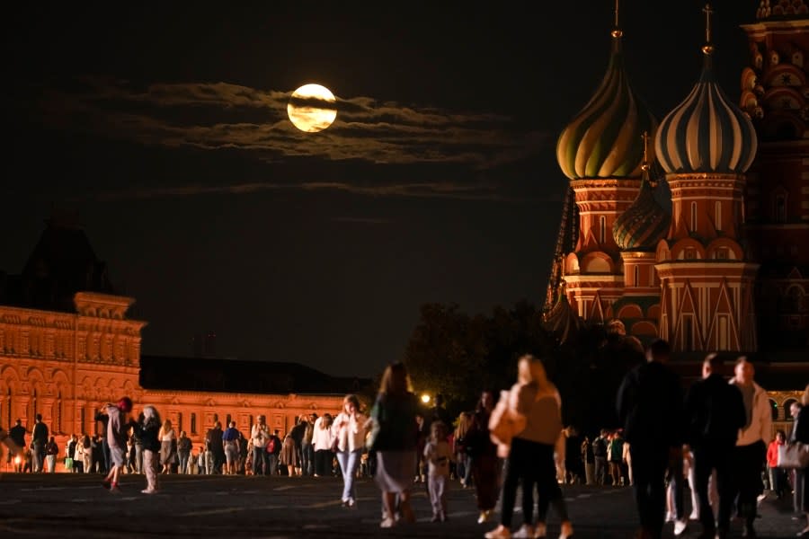 The August Super Blue Moon sets behind a historical building and the St. Basil’s Cathedral, right, as people walk in Red Square in Moscow, Russia, Wednesday, Aug. 30, 2023. The cosmic curtain rises Wednesday night with the second full moon of the month, the reason it is considered blue. It is dubbed a supermoon because it is closer to Earth than usual, appearing especially big and bright. (AP Photo/Alexander Zemlianichenko)