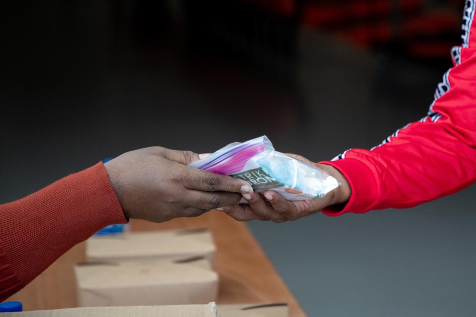 A Florida A&M University student picks up a COVID-19 kit which includes one disposable face mask, two reusable face masks, two bottles of hand sanitizer and a CDC flyer in the Al Lawson Center on the first day of fall semester classes Monday, August 24, 2020.