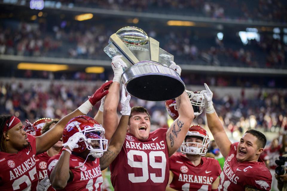 Sep 25, 2021; Arlington, Texas, USA; Arkansas Razorbacks defensive lineman Eric Thomas Jr. (37) and defensive lineman John Ridgeway (99) and linebacker Grant Morgan (31) hold up the Southwest Classic trophy as they celebrate the win over the Texas A&M Aggies at AT&T Stadium. Mandatory Credit: Jerome Miron-USA TODAY Sports