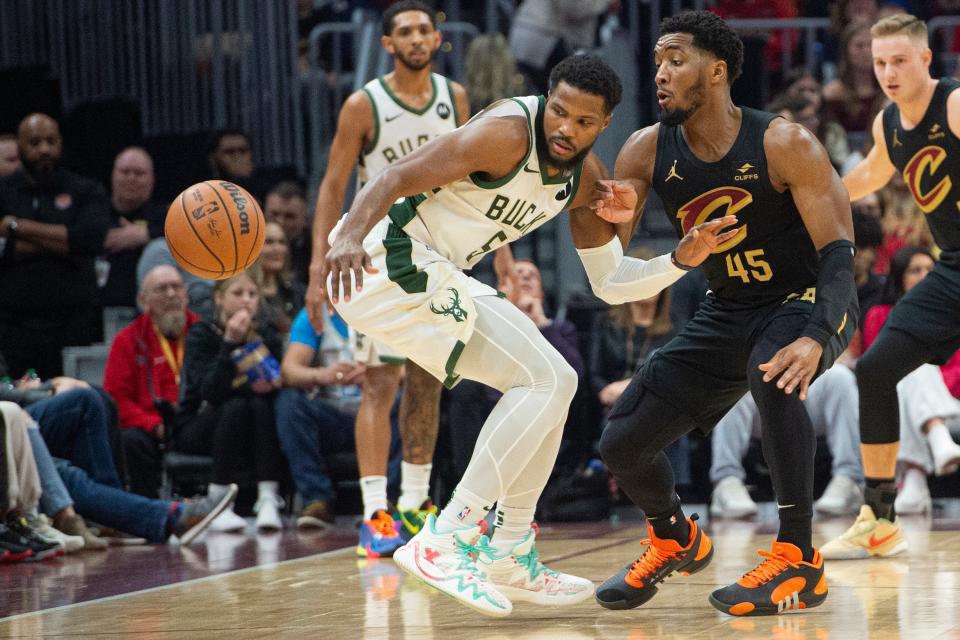 Milwaukee Bucks' Malik Beasley (5) goes for the ball as Cleveland Cavaliers' Donovan Mitchell (45) defends during the first half of an NBA basketball game in Cleveland, Friday, Dec. 29, 2023. (AP Photo/Phil Long)