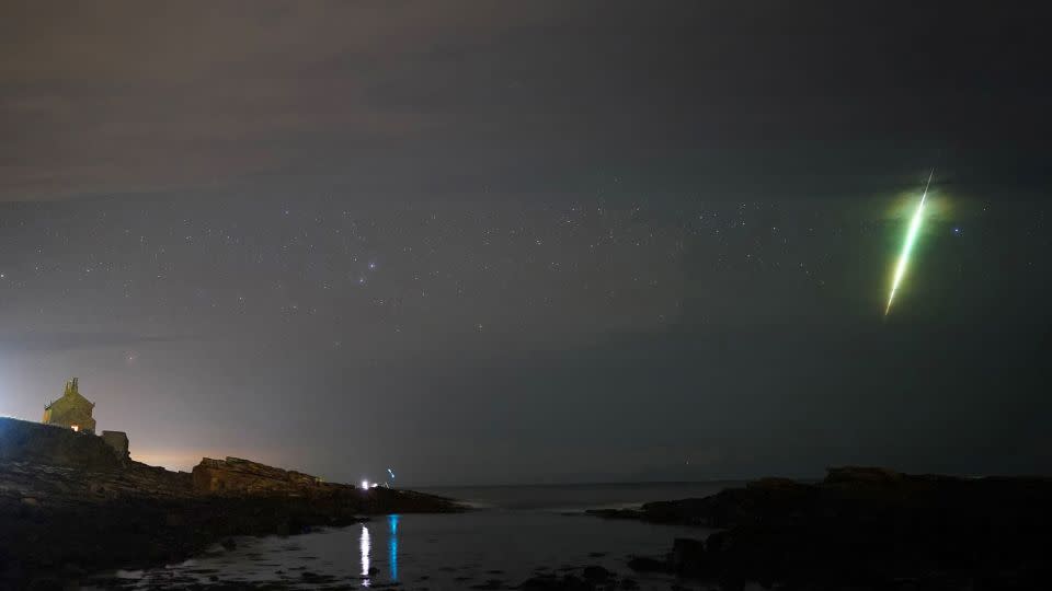 Un meteoro cruza el cielo durante la lluvia de meteoritos Dracónidas, vista sobre las rocas Howick en Northumberland, en el noreste de Inglaterra, en octubre de 2021. - Owen Humphreys/PA Media/ARCHIVO