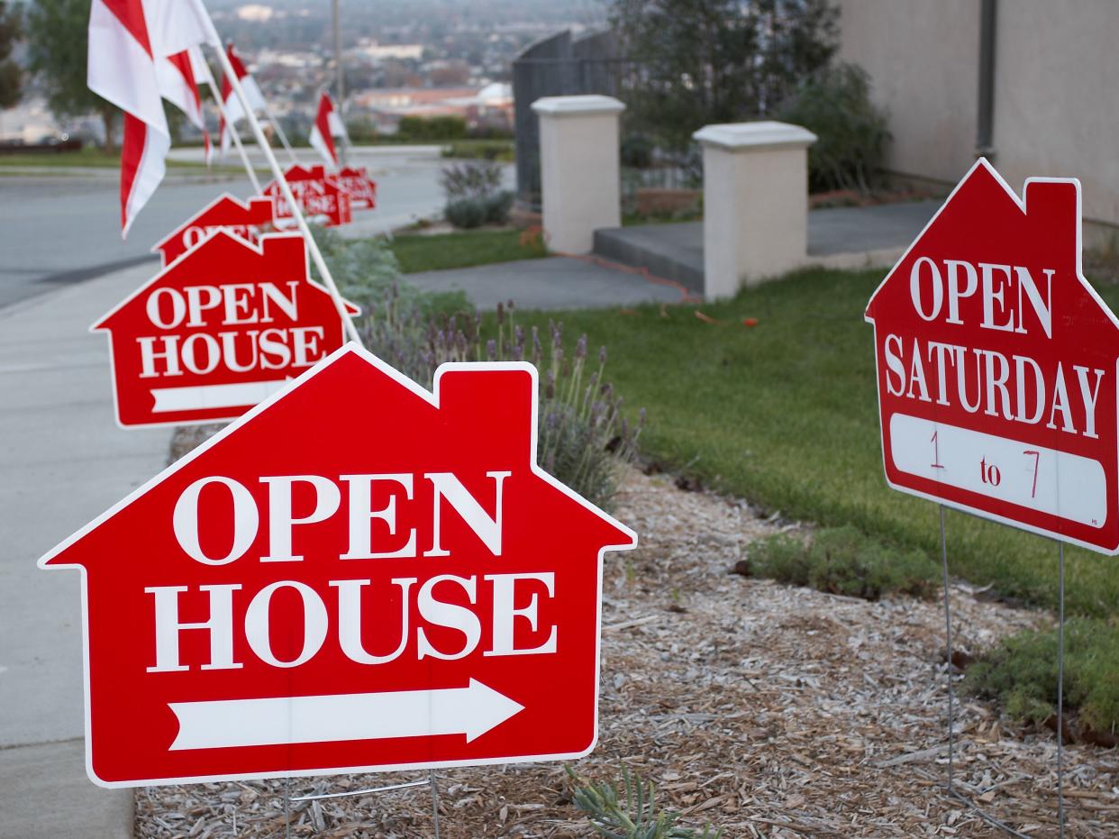 Red and white open house sign close-up with more signs in the background.