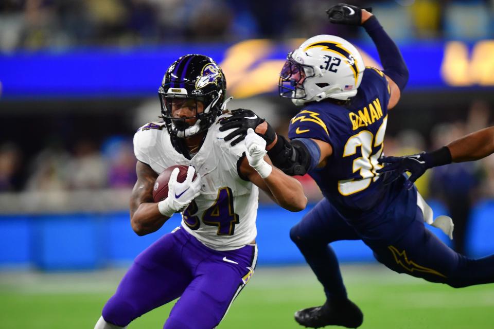 Baltimore Ravens running back Keaton Mitchell (34) runs the ball ahead of Los Angeles Chargers safety Alohi Gilman.