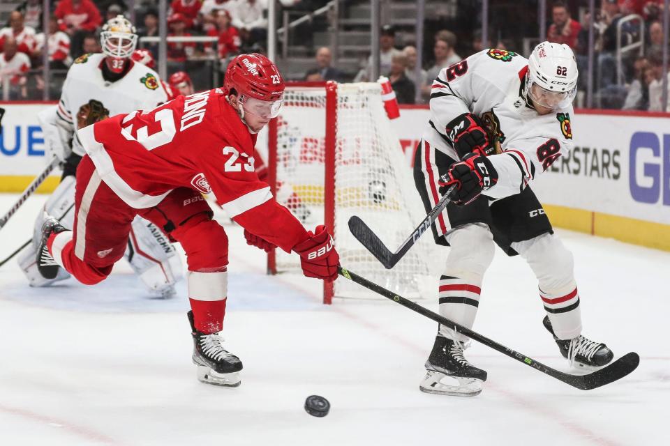 Blackhawks defenseman Caleb Jones makes a pass against Red Wings left wing Lucas Raymond during the first period on Wednesday, March 8, 2023, at Little Caesars Arena.