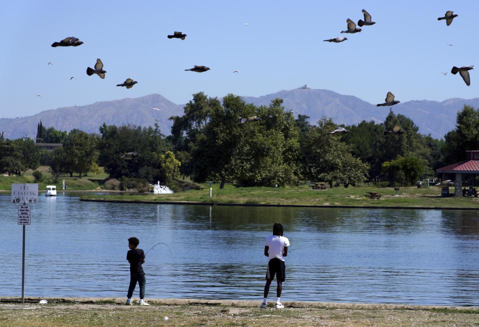 Young fishermen cast their lines along the banks of Balboa Lake in Balboa Park in Los Angeles on Wednesday, July 12, 2023. (AP Photo/Richard Vogel)