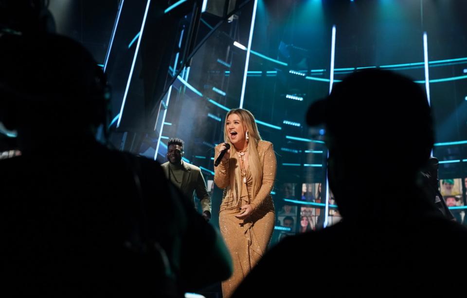 Kelly Clarkson signs on stage at the 2020 Billboard Music Awards