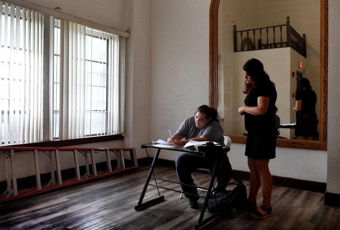 In the lobby of a midtown apartment building, Christina Smith, left, fills out paperwork while trying to gain residency there because her temporary home at a motel is expiring this weekend. Jennifer Hull, right, a street outreach worker is helping guide Smith through the process.