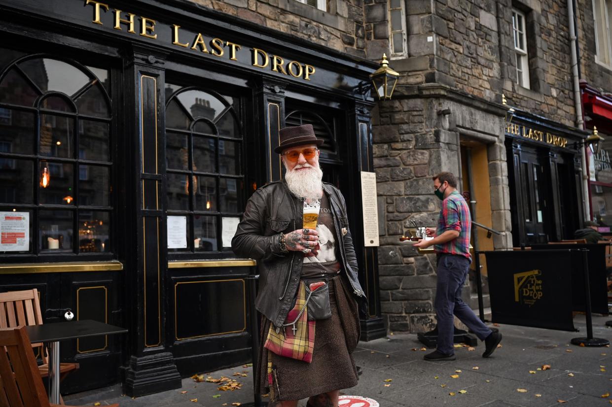 Charles Douglas Barr enjoys a pint outside The Last Drop pub in the Grassmarket on Oct. 7, 2020, in Edinburgh, Scotland. New restrictions seeing all pubs and restaurants across central Scotland to be closed under new measures aimed at tackling a surge in coronavirus cases announced by Scotland's first minister Nicola Sturgeon at the Scottish Parliament.