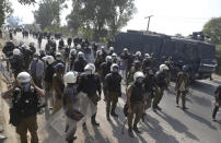 Police officers with riot gear try to stop supporters of Tehreek-e-Labiak Pakistan, a radical Islamist party, during a protest march toward Islamabad, on a highway in the town of Sadhuke, in eastern Pakistan, Wednesday, Oct. 27, 2021. Violence at the anti-France Islamist rally in Sadhuke left at least one police officer and two demonstrators dead. ​They demanded the expulsion of France's envoy to Pakistan over publication of caricatures of Islam's Prophet Muhammad in France. (AP Photo/K.M. Chaudary)