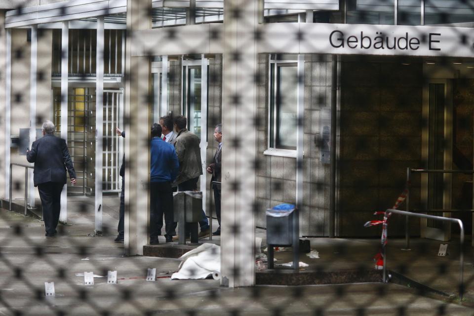 A covered body lies on the ground at the crime scene following a shooting at the entrance of Building E of the courthouse in Frankfurt January 24, 2014. REUTERS/Ralph Orlowski (GERMANY - Tags: CRIME LAW)