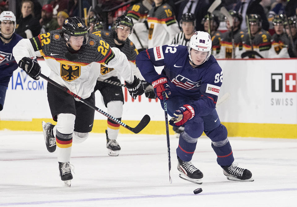 Germany's Philipp Bidoul (22) tries to catch United States' Logan Cooley, right, during second-period IIHF world junior hockey championships quarterfinal match action in Moncton, New Brunswick, Monday, Jan. 2, 2023. (Ron Ward/The Canadian Press via AP)
