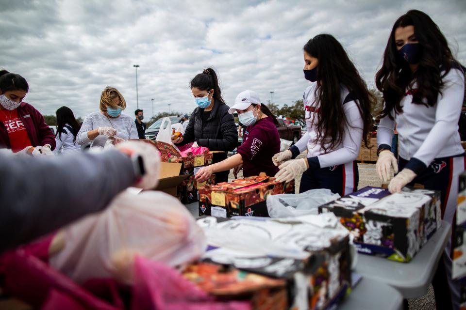 Texans Cheerleaders and other volunteers pack food to distribute to hundreds of people picking up supplies from their cars after frigid temperatures left the Houston area depleted of resources, Sunday, Feb. 21, 2021, in Houston. 