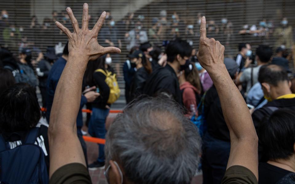 Pro-democracy activists gesture 'five demands, not one less' in support of those arrested in Hong Kong - JEROME FAVRE/EPA-EFE/Shutterstock 