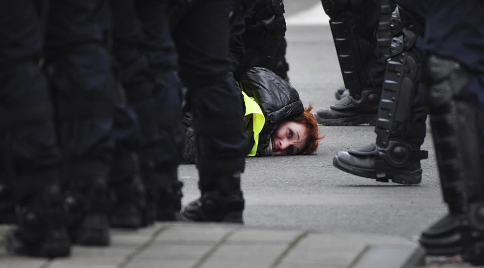 A woman in a yellow vest is detained by police during a demonstration in Brussels, Saturday, Dec. 8, 2018. Hundreds of police officers are being mobilized in Brussels Saturday, where yellow vest protesters last week clashed with police and torched two police vehicles. More than 70 people were detained. (AP Photo/Geert Vanden Wijngaert)