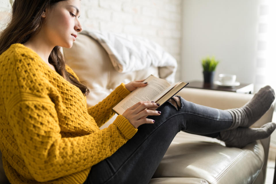 Side view of woman concentrating on reading a book while resting in sitting room