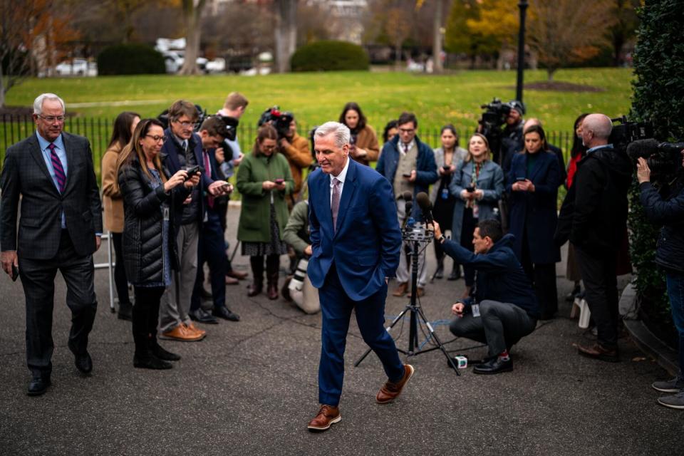 A man in a suit walks away from several people standing outdoors.