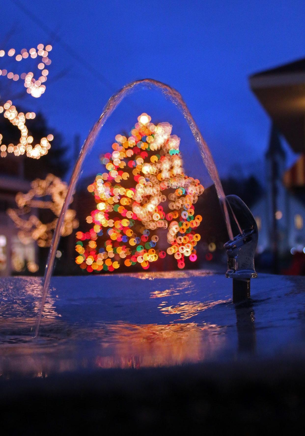 The glow of the Harbor Springs Christmas tree shines under the arch of a water fountain in downtown Harbor Springs. The Merchant's Holiday Open House will be from 6-9 p.m. Saturday, Dec. 3.