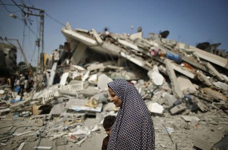 A Palestinian woman walks past the rubble of a residential building, which police said was destroyed in an Israeli air strike, in Gaza City July 22, 2014. REUTERS/Mohammed Salem