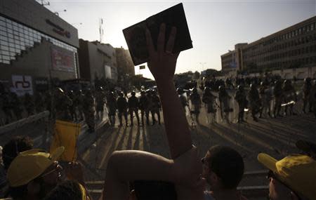 A supporter of the Muslim Brotherhood and ousted Egyptian President Mohamed Mursi shouts slogans and holds a copy of the Koran, in front of army soldiers and riot police, during a protest against the military near Rabaa al-Adawiya square in Cairo, October 4, 2013. REUTERS/Amr Abdallah Dalsh